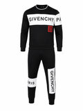 A black Givenchy two-piece tracksuit featuring a long-sleeve sweatshirt and matching jogger pants. The sweatshirt has a white chest panel with 'GIVENCHY' printed in black, a red Givenchy logo patch on the chest, and 'PA' printed on the sleeve.